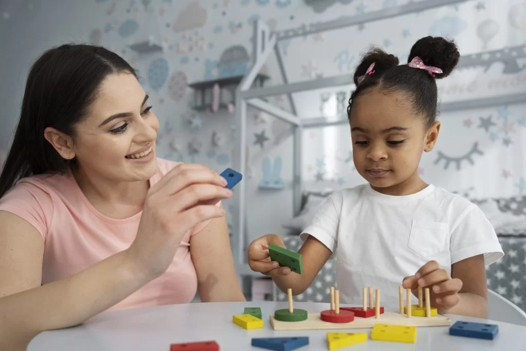 Child fitting shape blocks during a hands-on therapy activity