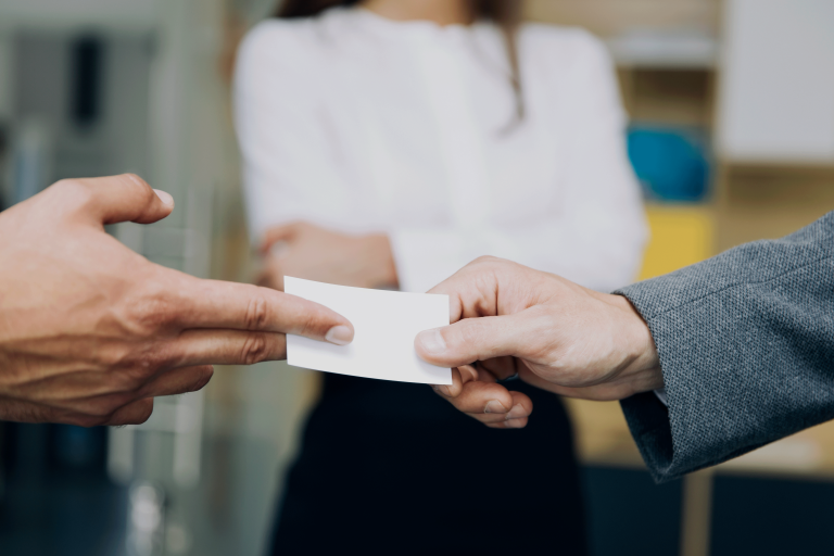 Close in shot of a person handing over a business card to another