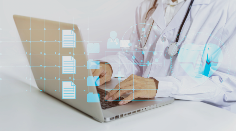 Medical professional in a white coat typing on a laptop