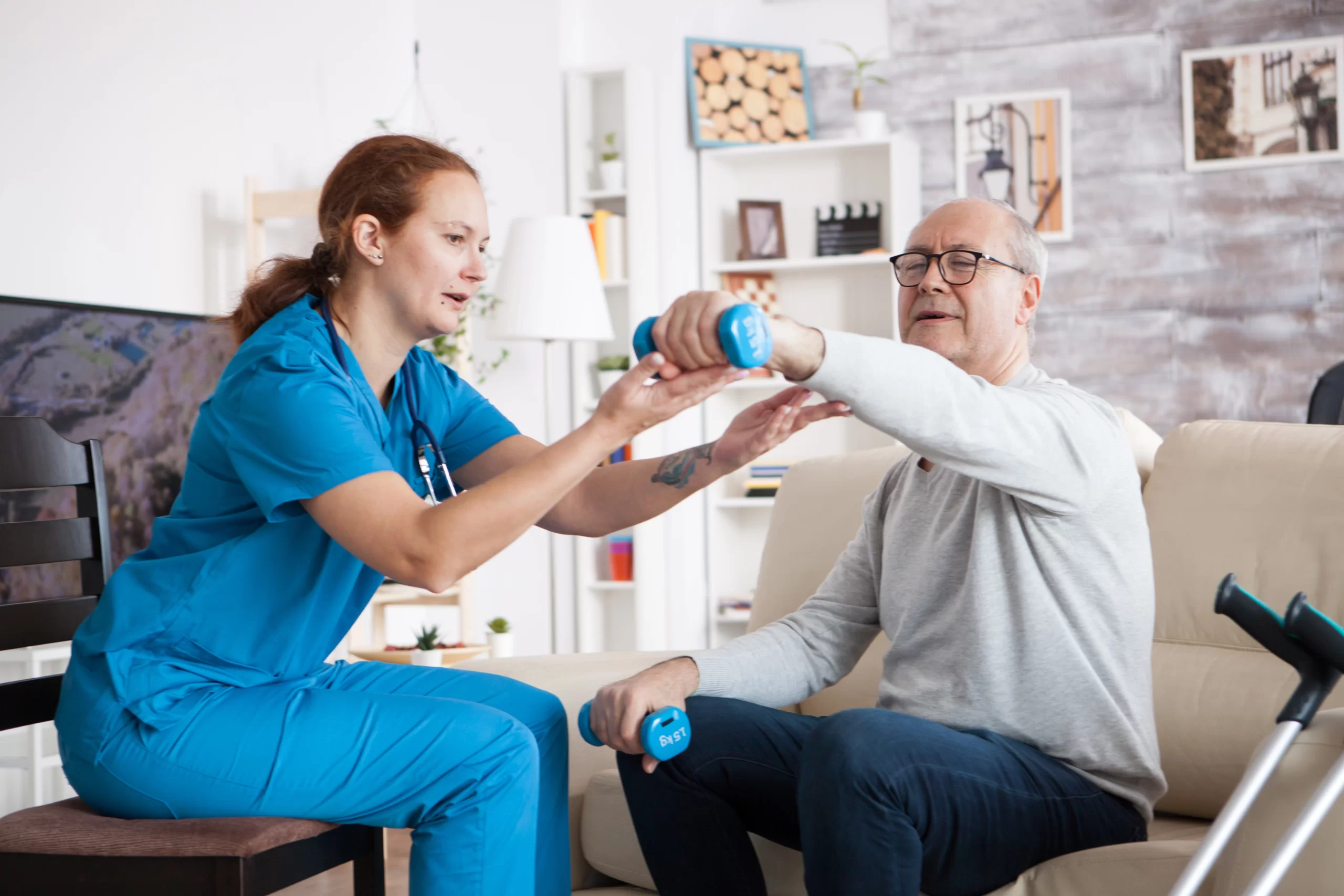 Senior man doing seated exercises with light dumbbells alongside a physical therapist
