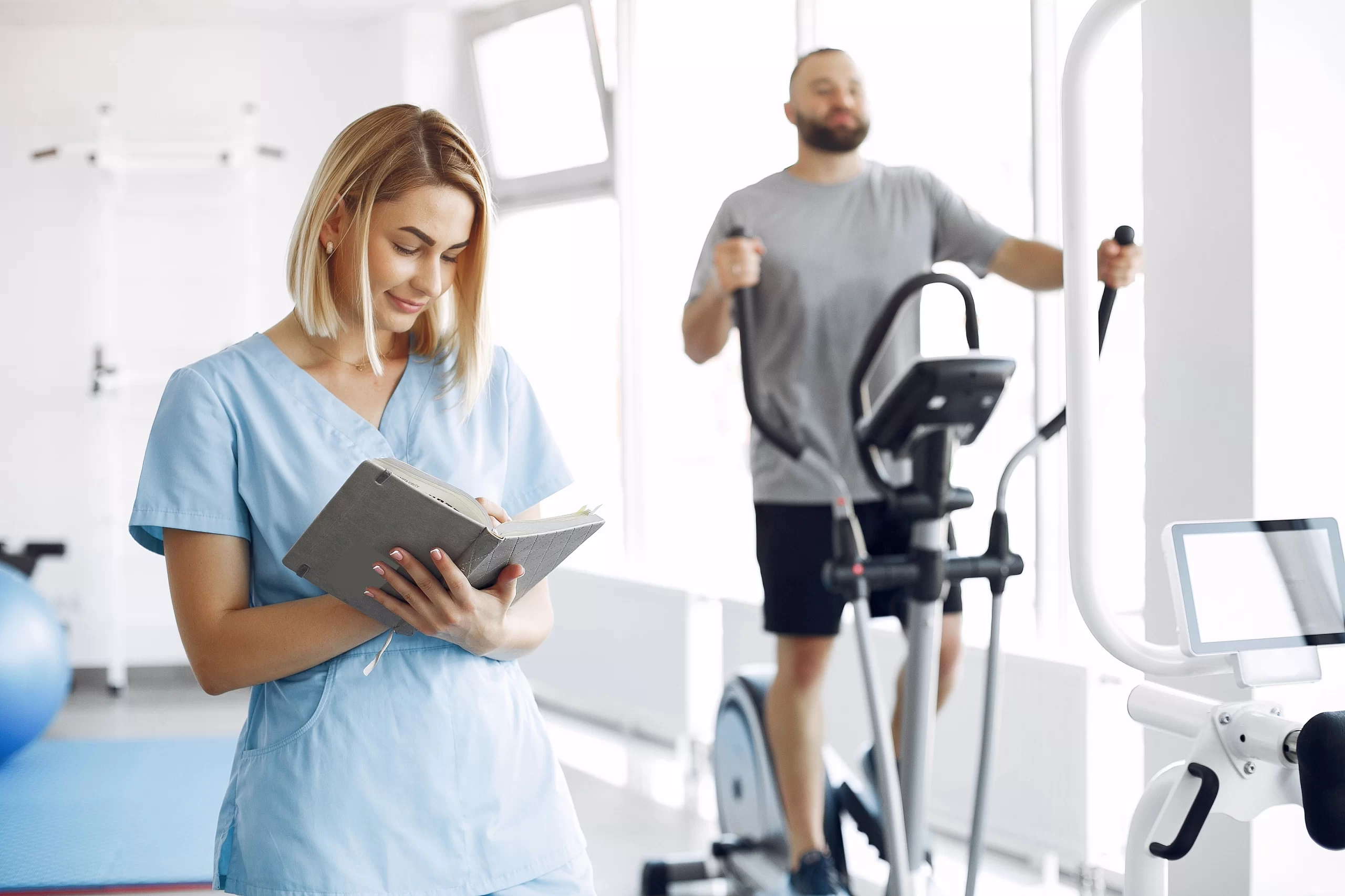 Patient pedaling a stationary exercise bike while a clinician monitors the session