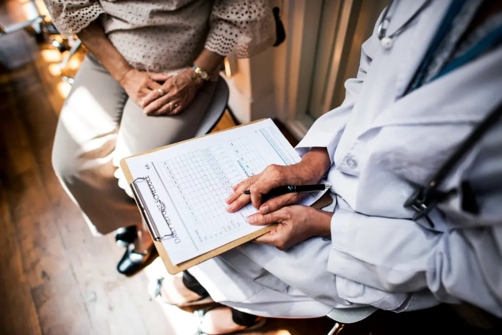 A patient sits in a consultation room speaking with a doctor during a medical appointment.