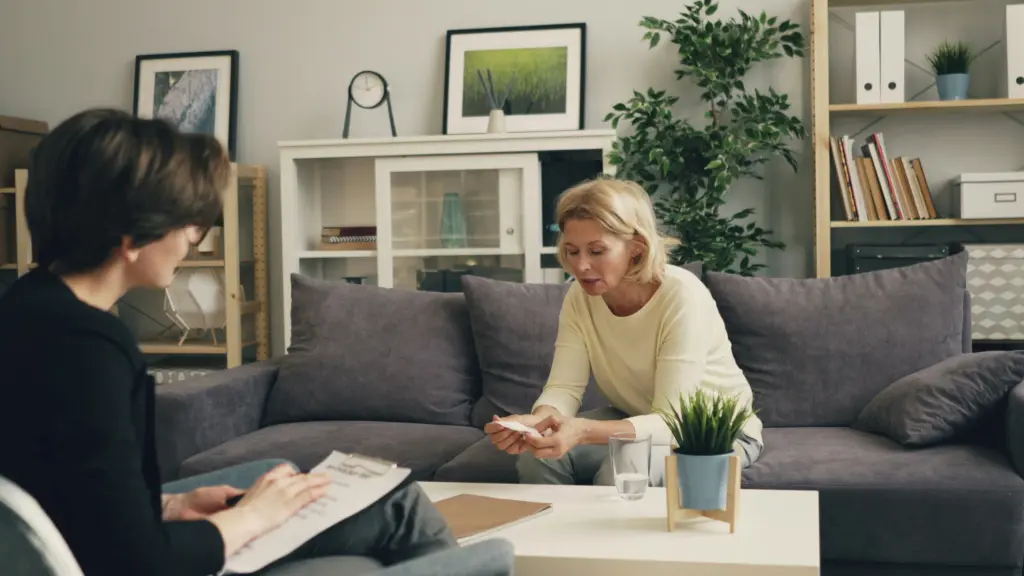 Therapy session, a woman sitting on a couch talking to another woman.
